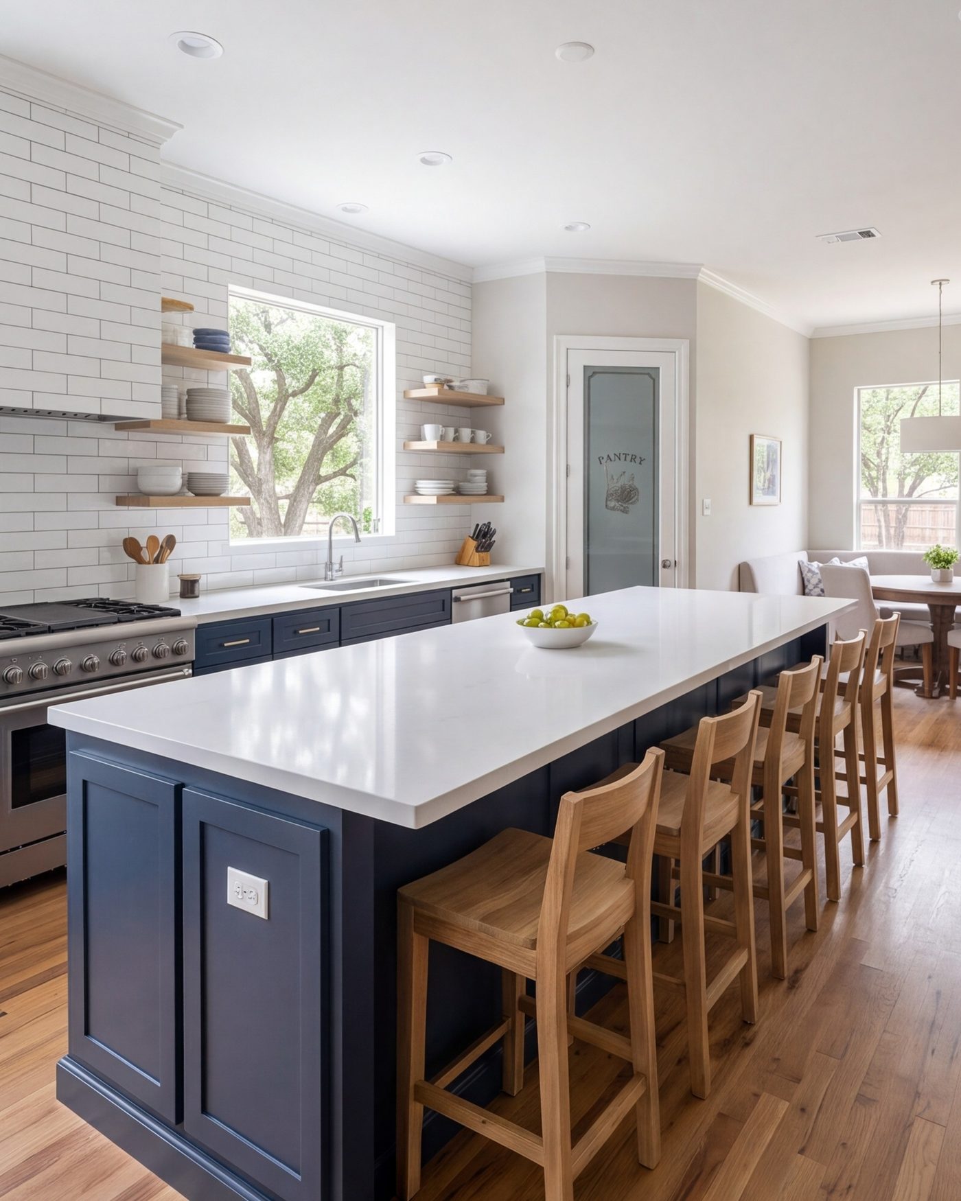 Spacious remodeled kitchen with a long island, bar stools and a walk-in pantry door in a Cinco Ranch home